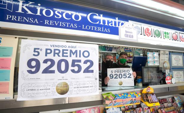 Padre e hijo muestran un cartel del premio que han repartido en su kiosco de Plaza Nueva, donde se ha vendido el quinto. 