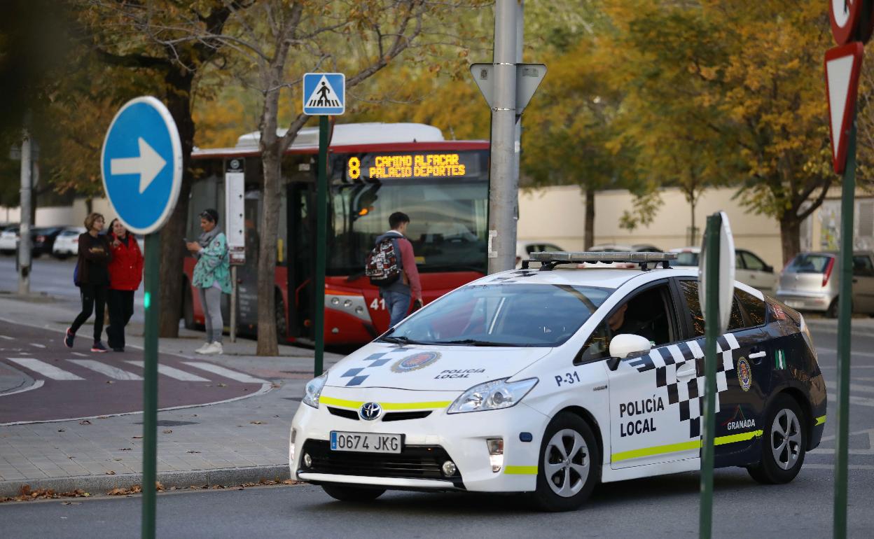 Un coche patrulla de la Policía Local, junto a un bus urbano.