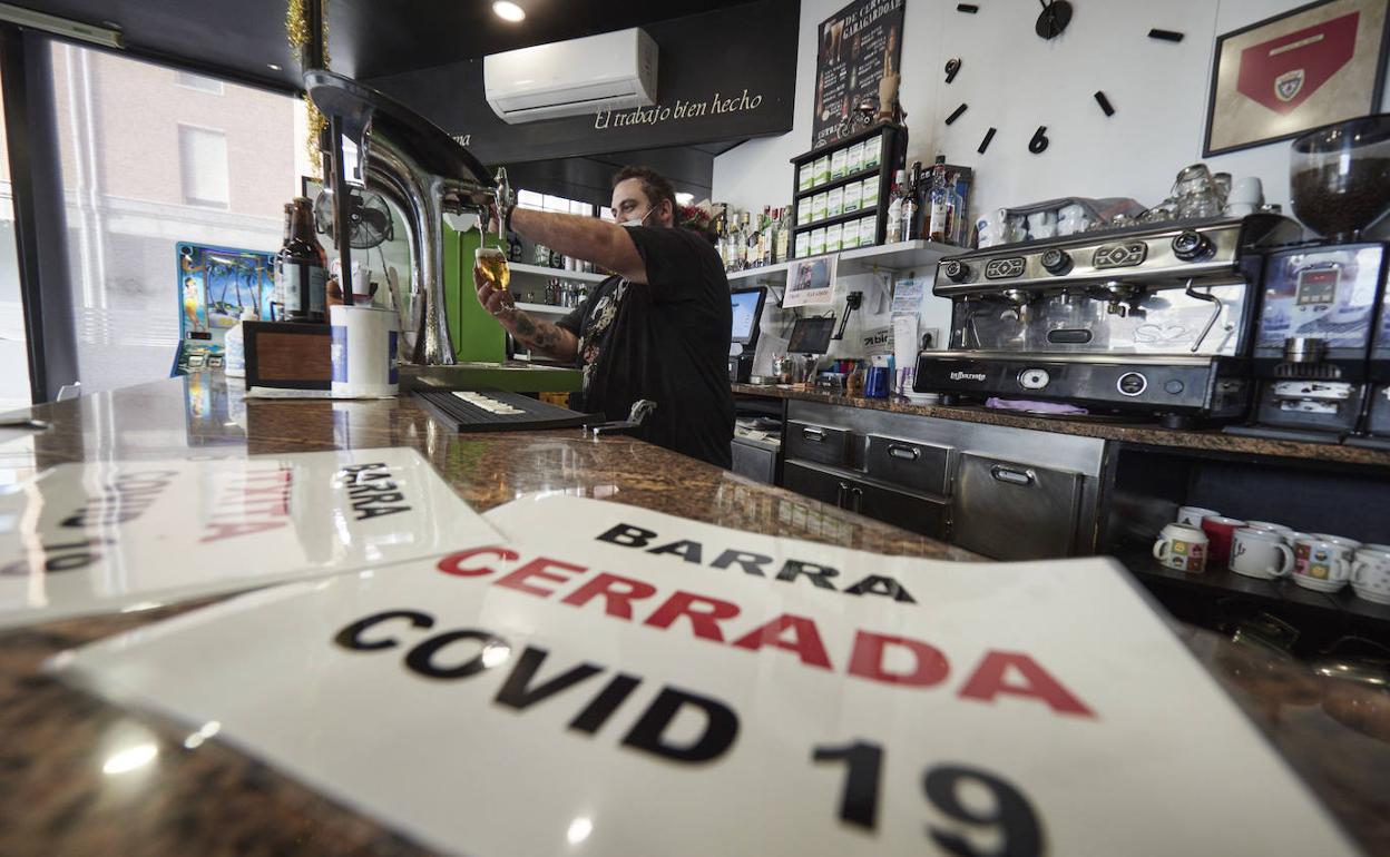 Un camarero de un bar atiende el mismo día en que han entrado vigor nuevas restricciones en Navarra