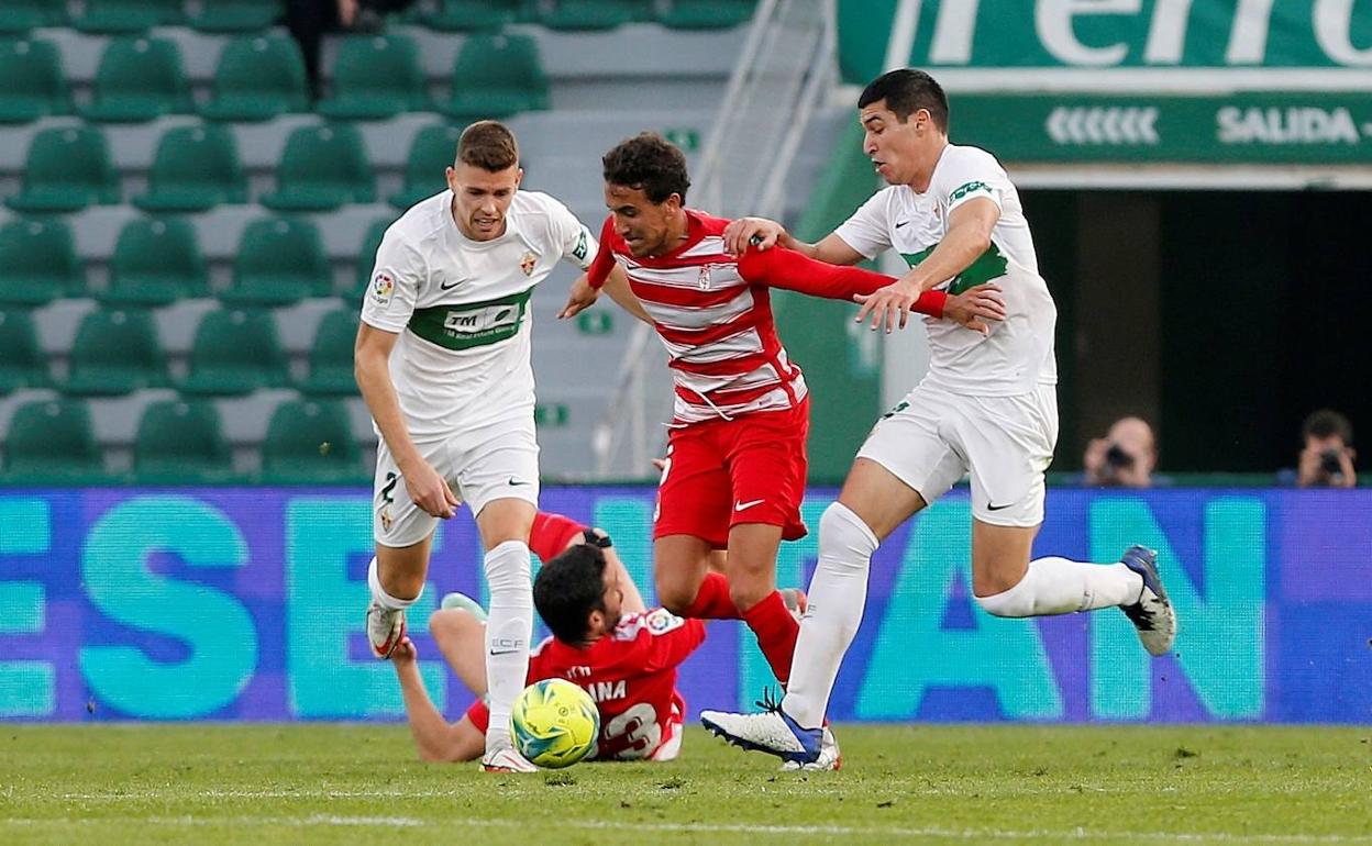 Dos futbolistas del Elche intentan frenar a Luis Milla. 