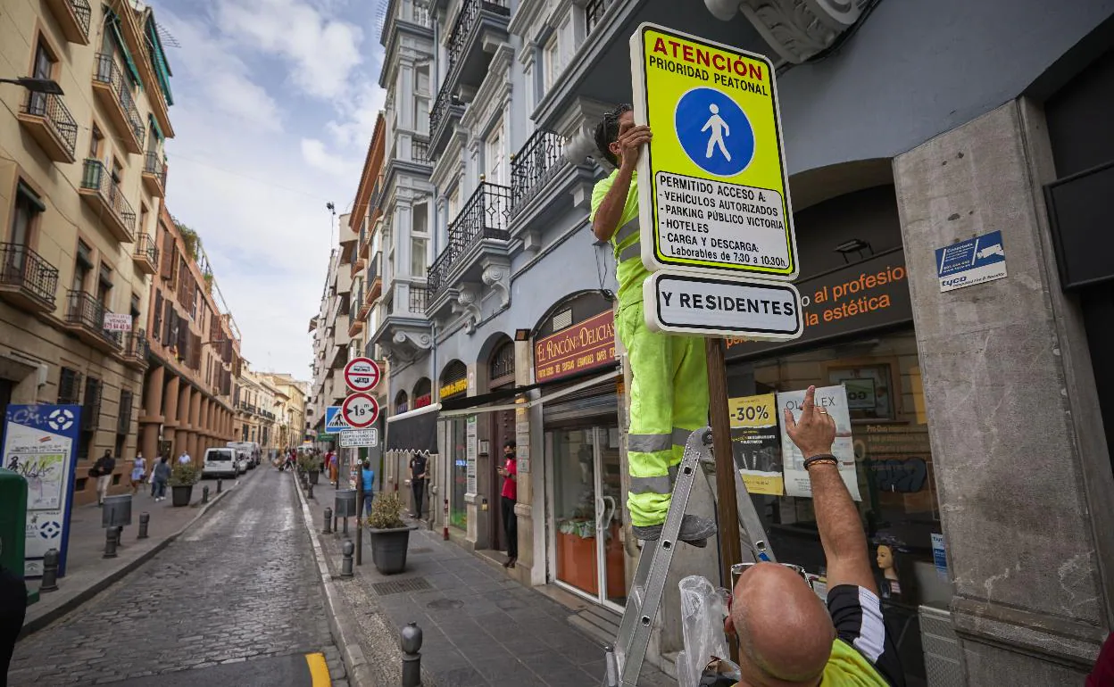 Operarios ponen una señal que informa de la peatonalización en la calle San Antón.