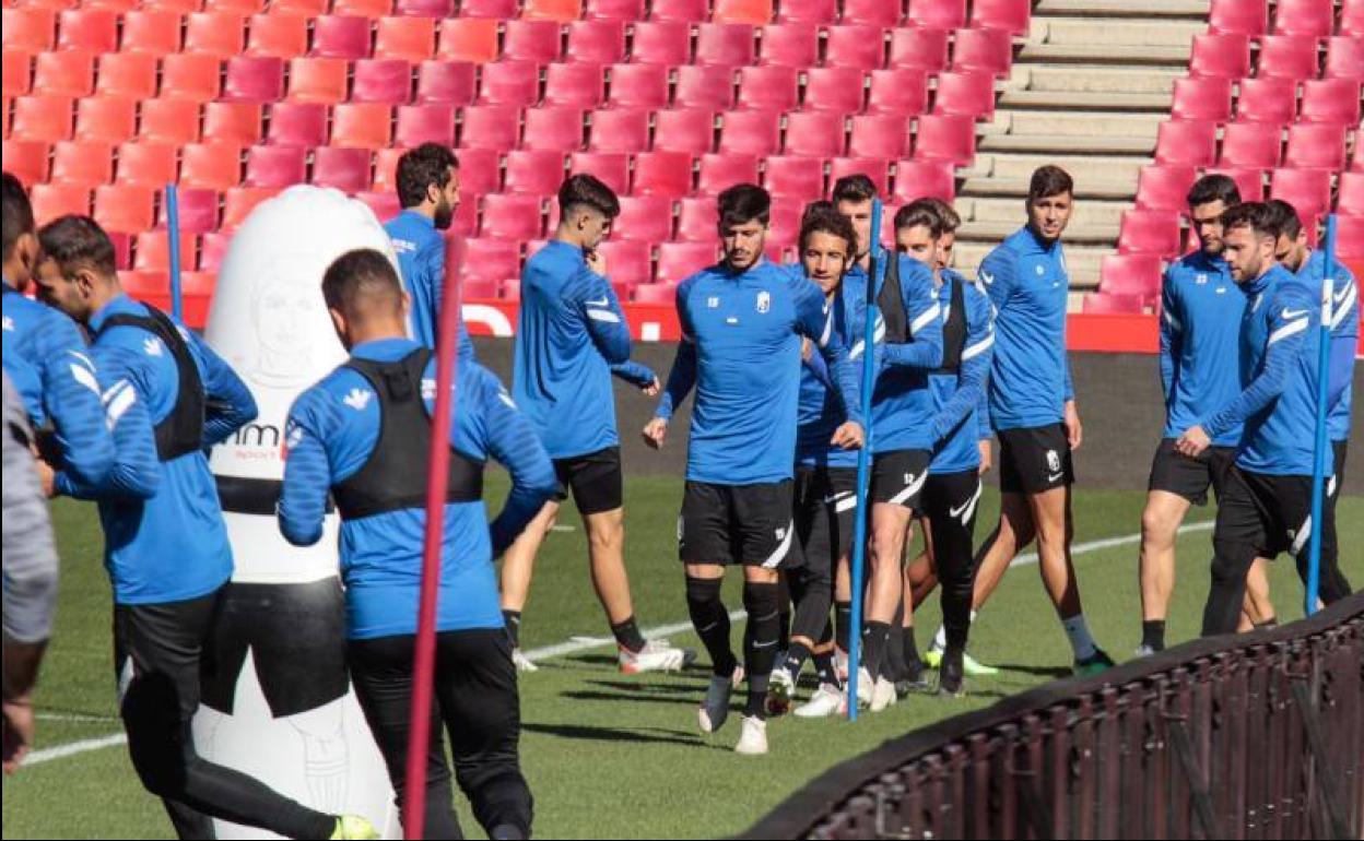 Los futbolistas del Granada calientan antes de entrenar el viernes en Los Cármenes. 