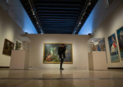 Imagen secundaria 1 - Arriba, cartel de la exposición. Abajo, panorámica con el cuadro 'Velatorio' de López-Mezquita al fondo, y autorretrato de Zuloaga con su biznieto Ignacio. 