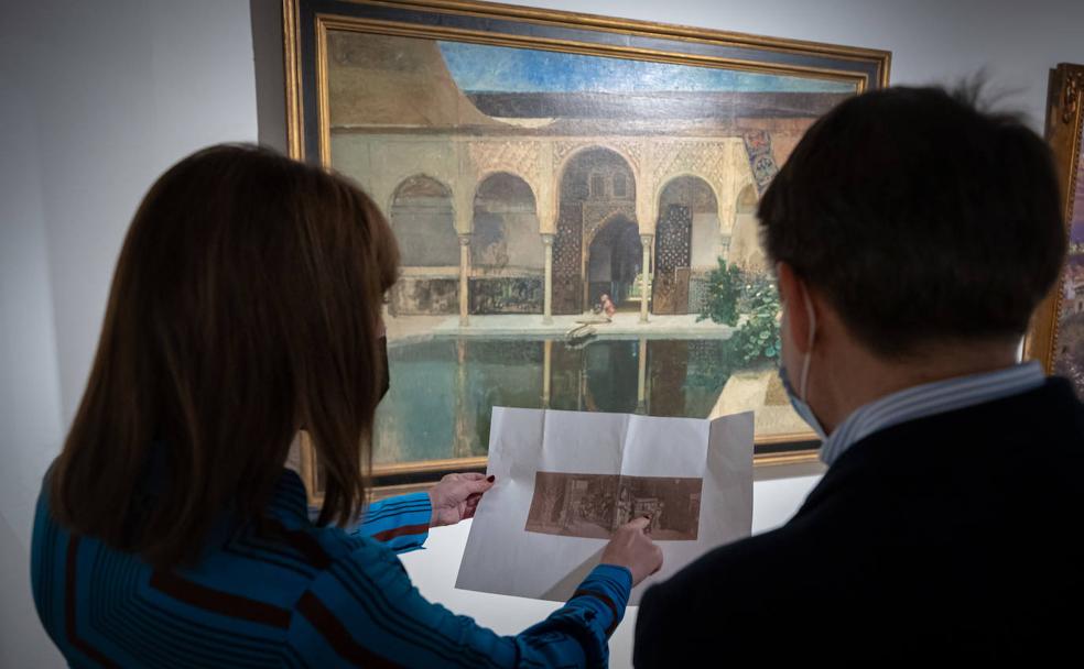 Rocío Díaz señala la fotografía tomada en 1873 donde está la pintura 'El Patio de la Alberca de la Alhambra', frente a la obra expuesta en la Capilla del Palacio de Carlos V. 