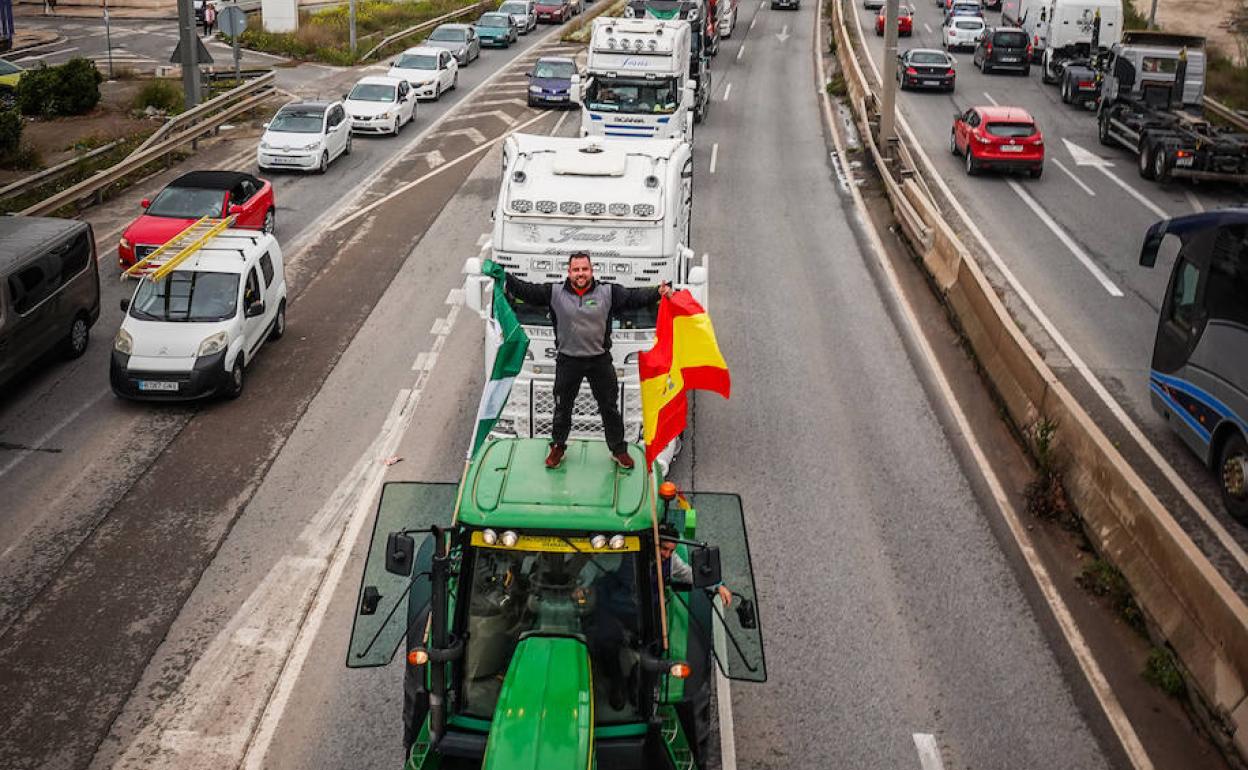 Un agricultor subido en el techo de un tractor en primer plano de la caravana de camiones a su paso por la Avenida de Andalucía de la capital, donde se generaron más problemas. 