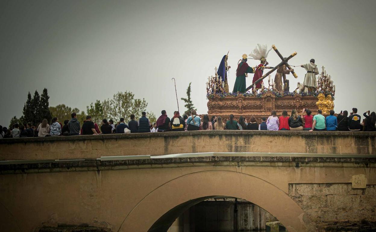 La hermandad del Trabajo y la Luz procesiona sobre el puente romano. 