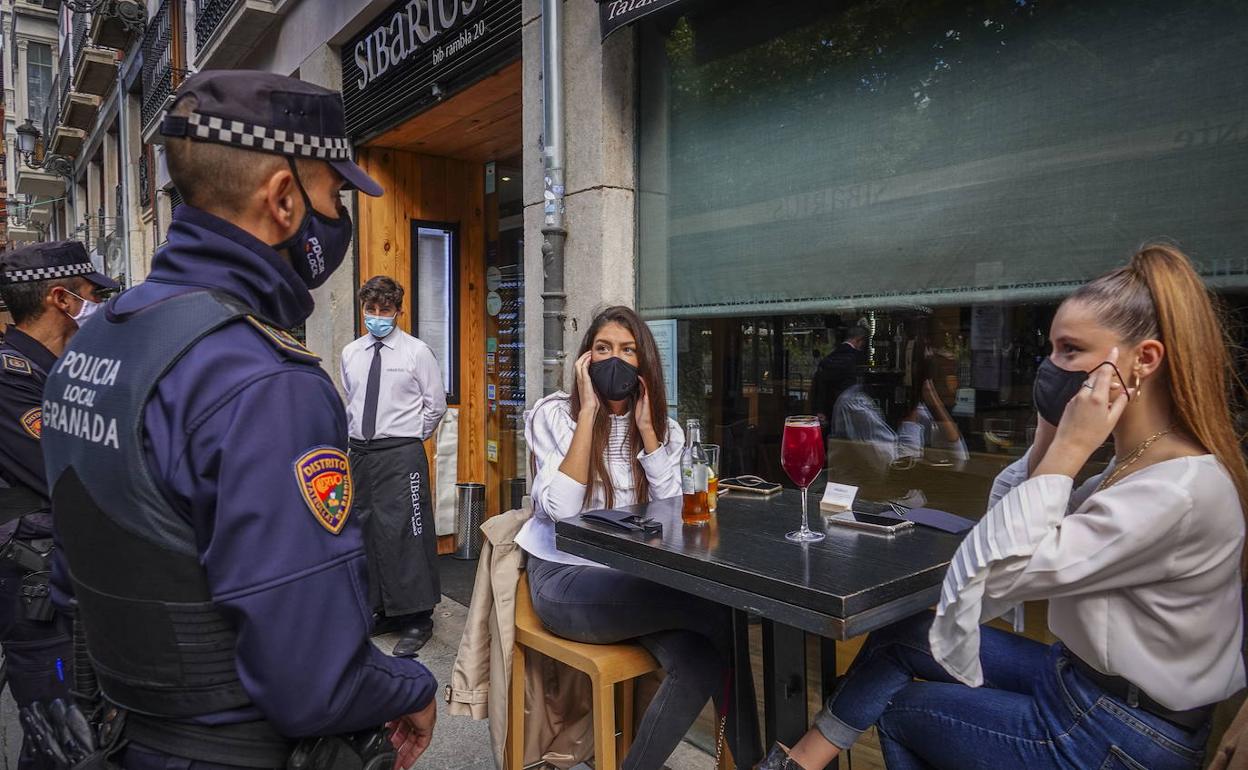 Un agente de policía informa a clientes de un bar de la obligatoriedad de llevar mascarilla en una imagen de archivo. 