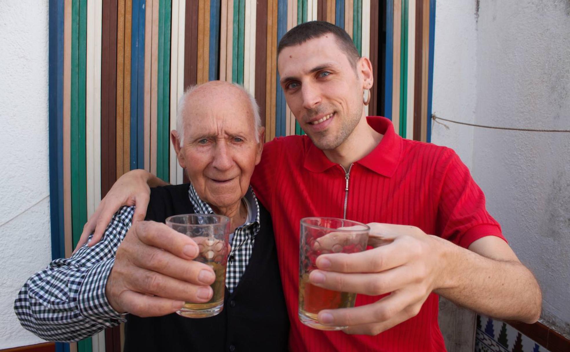 Antonio y Fran, abuelo y nieto, brindan con vino en la entrada de la casa.