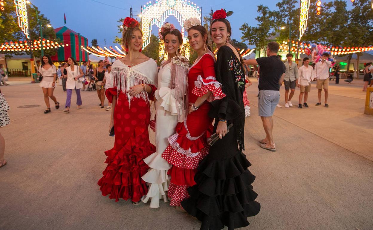 Cuatro chicas vestidas de flamenca se disponen a disfrutar de la noche del viernes en el ferial. 