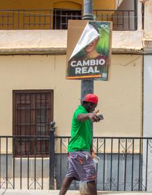 Imagen secundaria 2 - Tres adolescentes de Albuñol, en la plaza del Ayuntamiento de la localidad. Un vecino pasa junto a la sede local del PSOE y una carnicería halal. Un migrante camina bajo una banderola de Vox.