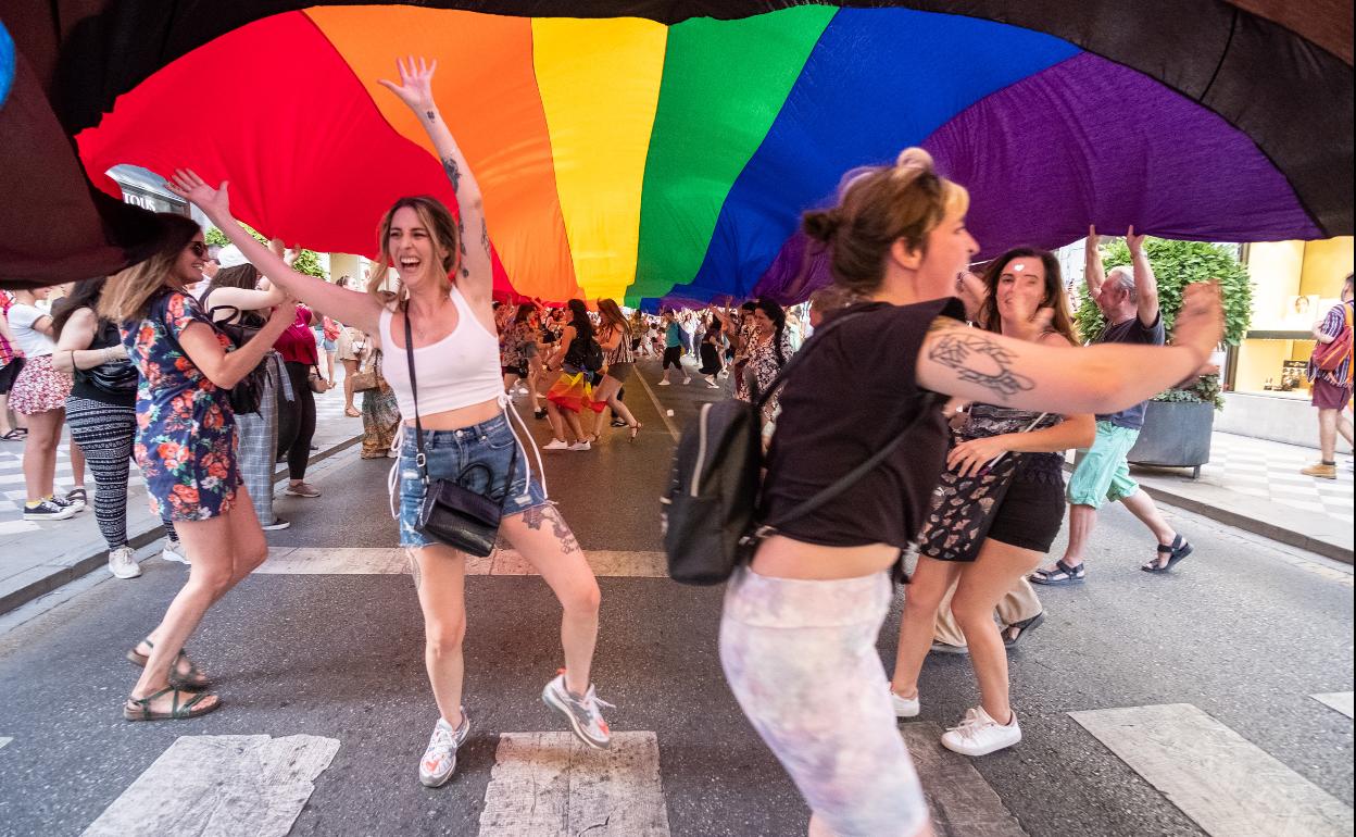 Una bandera multicolor gigante precedía a un autobús de dos pisos.