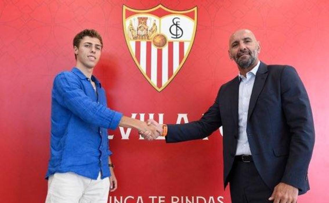 Juancho Villegas posa ante el escudo sevillista con Monchi. 