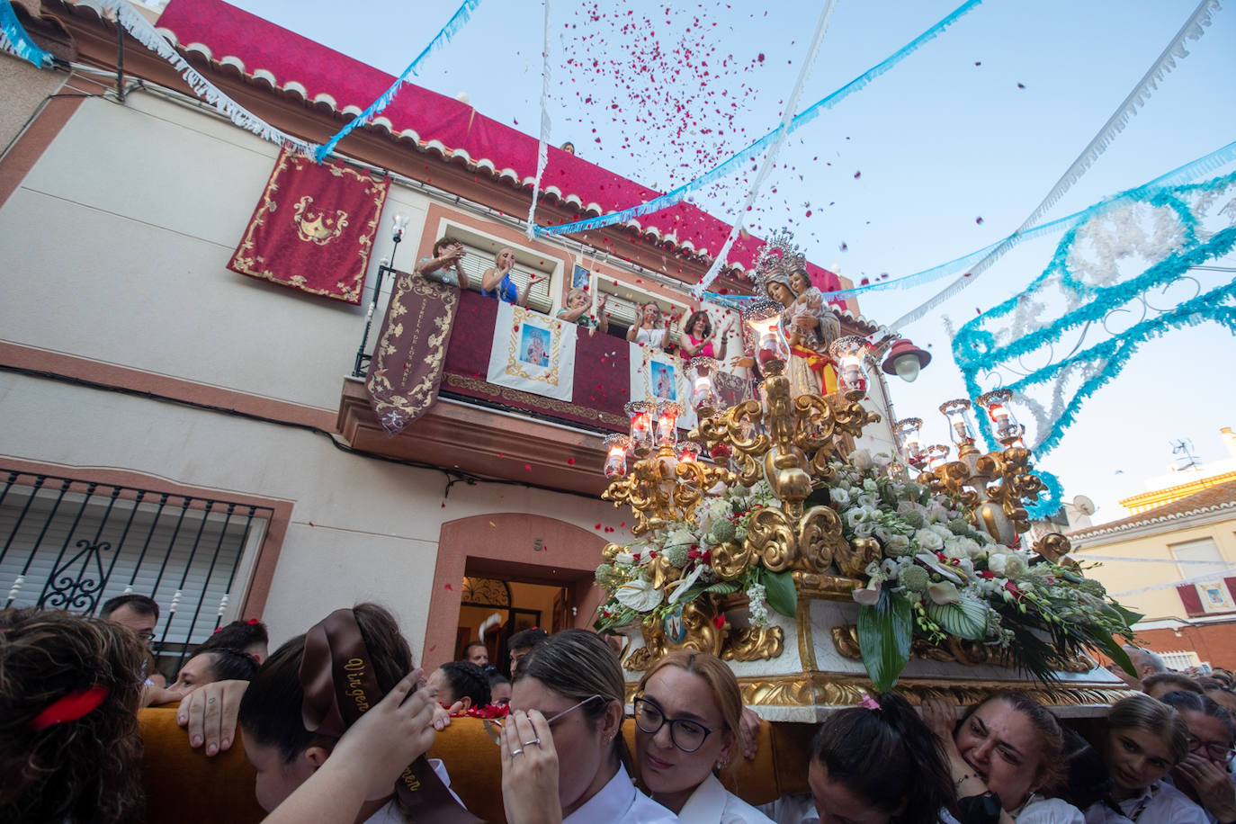 El trono de la Virgen del Carmen recibe una petalá a su paso por una de las calles de Varadero en Motril.