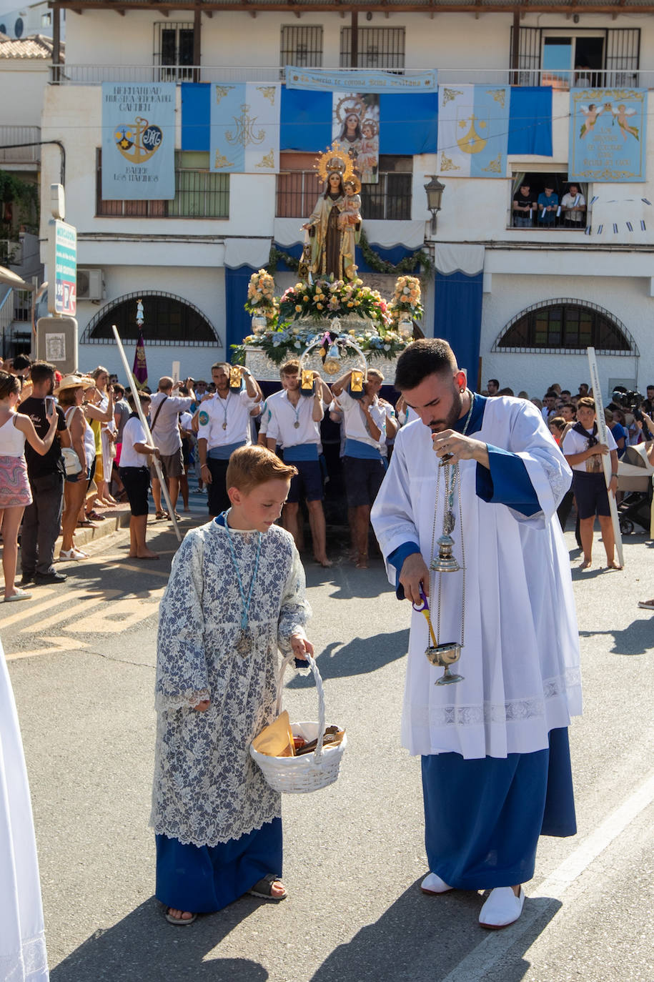 La Virgen del Carmen de Almuñéca, con el Barrio de Los Marinos al fondo, enfila la playa de San Cristóbal tras salir de la capilla.