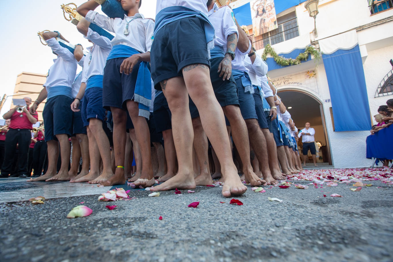 La Virgen del Carmen de Almuñéca, con el Barrio de Los Marinos al fondo, enfila la playa de San Cristóbal tras salir de la capilla.