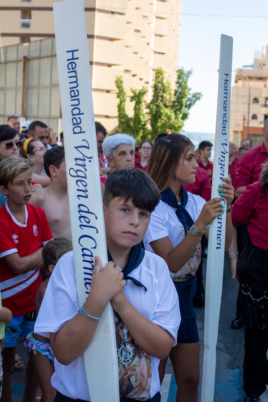 La Virgen del Carmen de Almuñéca, con el Barrio de Los Marinos al fondo, enfila la playa de San Cristóbal tras salir de la capilla.