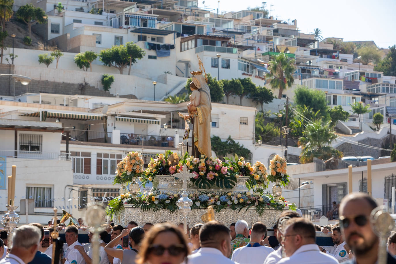 La Virgen del Carmen de Almuñéca, con el Barrio de Los Marinos al fondo, enfila la playa de San Cristóbal tras salir de la capilla.