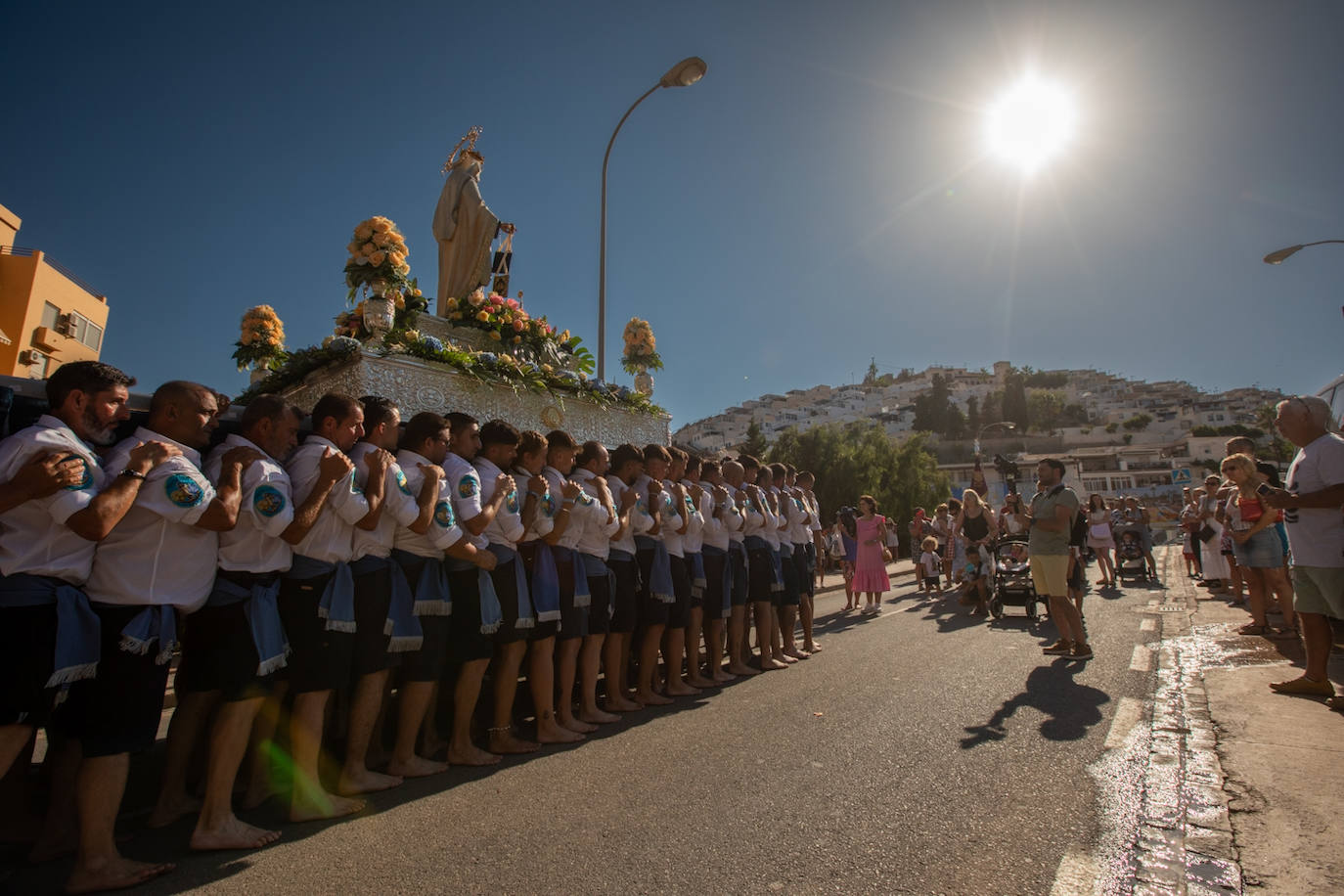 La Virgen del Carmen de Almuñéca, con el Barrio de Los Marinos al fondo, enfila la playa de San Cristóbal tras salir de la capilla.