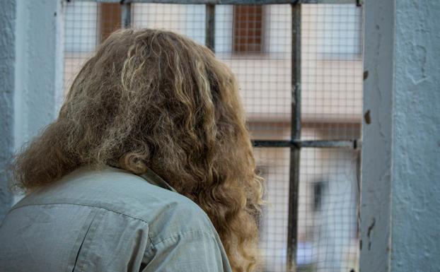 Una mujer mira por la ventana hacia el edificio rehabilitado.