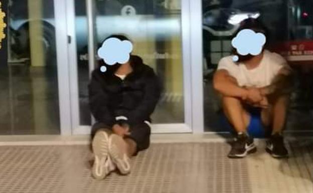 Los dos detenidos, sentados en el suelo, a la espera de ser trasladados a dependencias policiales.