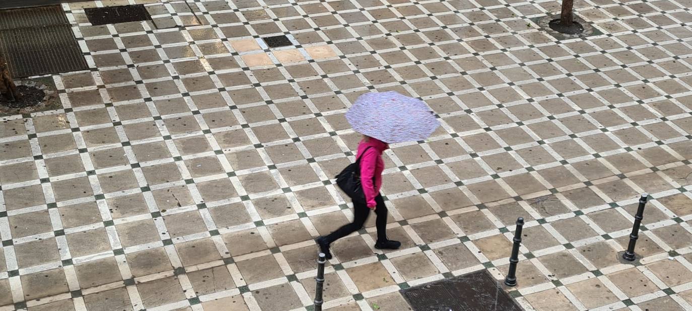 Viandante este miércoles salta un charco en la calle Navas de Tolosa de Jaén capital. 