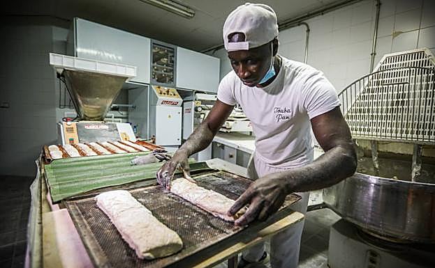 Imagen principal - Ibrahima cocina y vende el pan en su panadería de Otura.