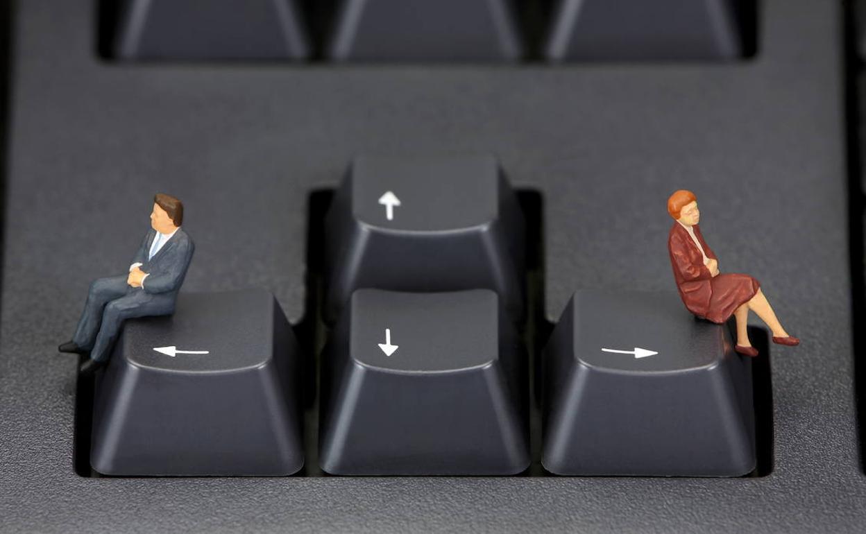 Figura de hombre y de mujer sentados en dos teclas opuestas de un teclado del ordenador. 