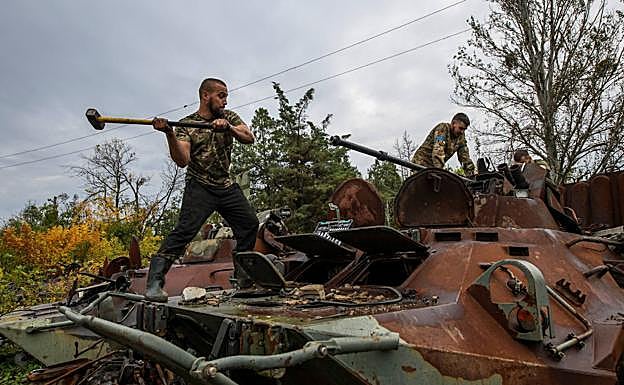 Imagen principal - Arriba, un voluntario ucraniano destruye los restos de un tanque en Izium. Abajo, el coronel Safonov e investigadores en una fosa común.