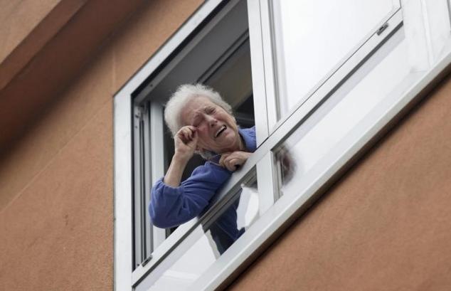 Carmen, vecina del concello coruñés de Cambre, celebra por la ventana el premio Gordo que ha tocado en el bar de debajo de su casa