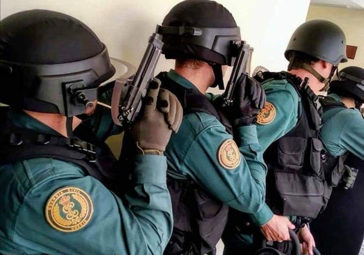 Agentes de la Guardia Civil irrumpen pistola en mano en una vivienda para una intervención.