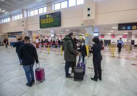Unos viajeros esperan en el vestíbulo del Aeropuerto de Granada.