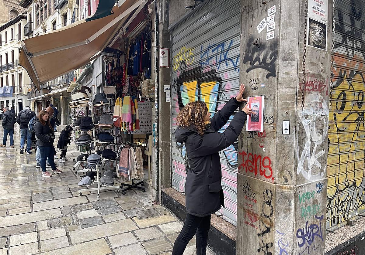 Ruth Montiel pega carteles en la zona del mercado de la Romanilla de Granada, este domingo.