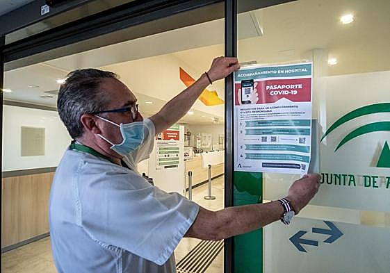 Un sanitario cuelga el cartel informativo sobre el pasaporte covid, en febrero de 2022.