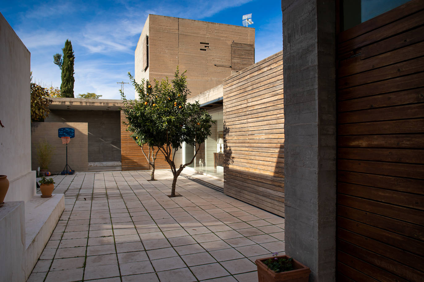 Imagen - Patio con naranjos con 'burladeros' para controlar luz y temperatura; al fondo, torre con dormitorios.