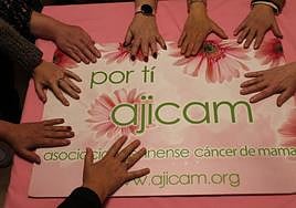 Mujeres con cáncer de mama posan sobre el cartel de Ajicam en Jaén.