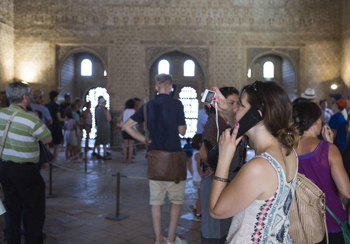 Una turista escucha la descripción del monumento nazarí en una audioguía.