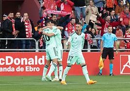 Puertas y Quini se abrazan, con José Callejón al lado, mirando al público.