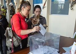 Una granadina deposita su voto ante la mirada de su mascota.