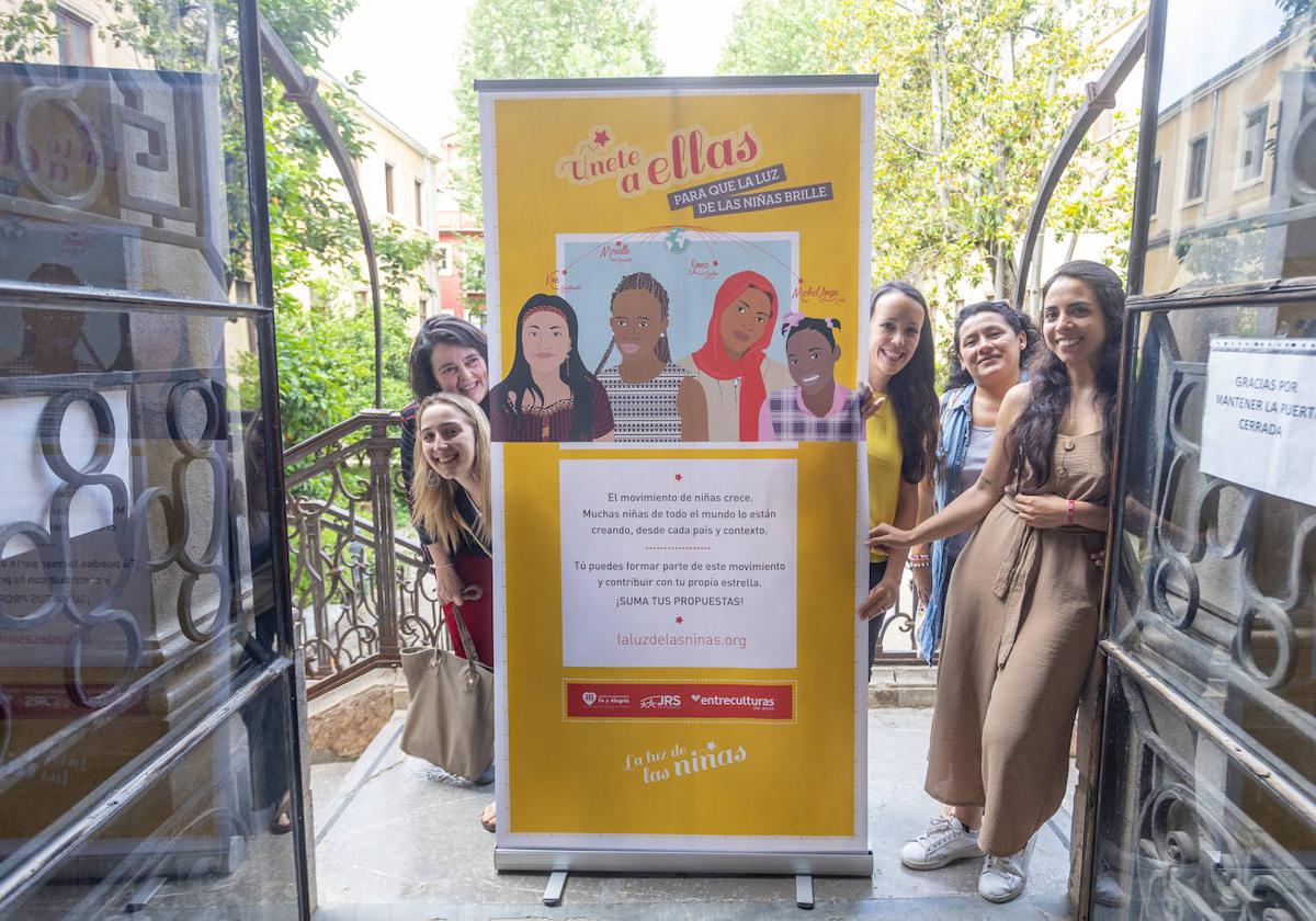 Representantes de la ONG Entreculturas y alumnas de la Facultad de Traducción junto a uno de los paneles de la exposición.