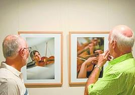 Dos asistentes observan algunas de las fotos de la exposición.