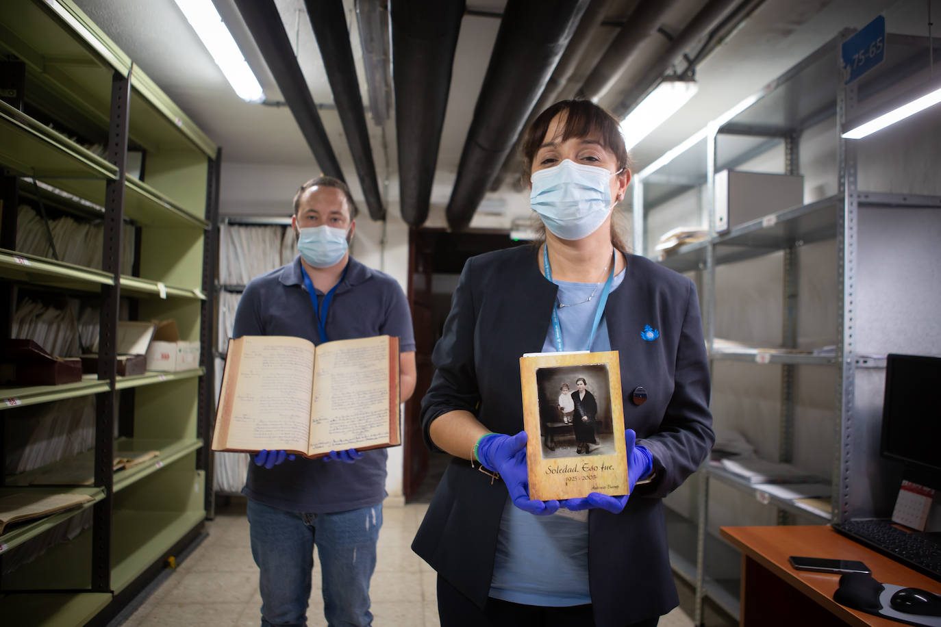 Vanessa y Vicente con el libro sobre Soledad y el documento con sus datos de defunción.