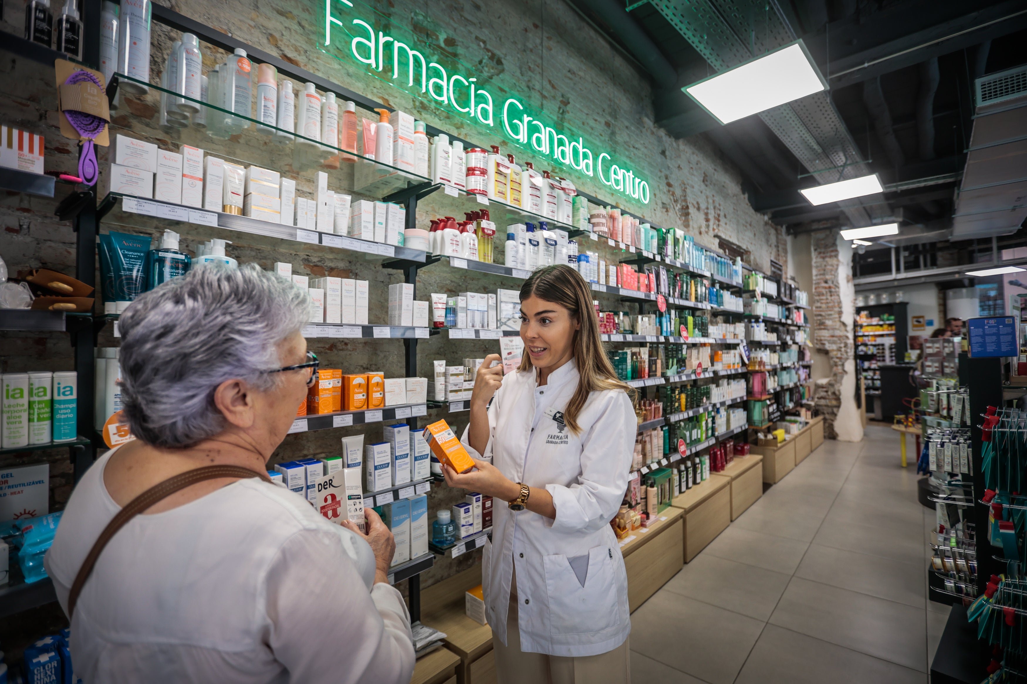 Una farmacéutica y una clienta, sin mascarilla, por primera vez en meses.