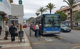 Varias personas se acercan a la parada de autobuses.