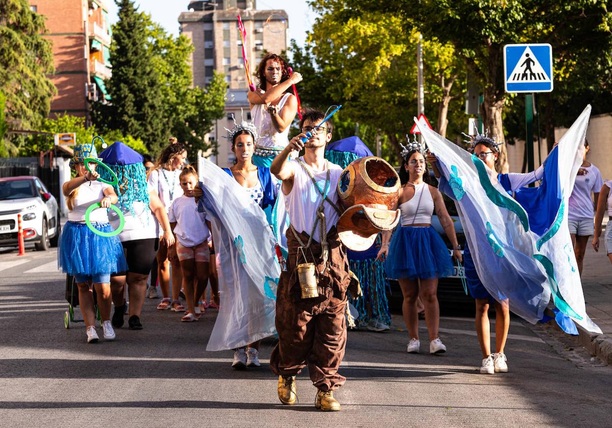 El pasacalles por el barrio de Cartuja anuncia los talleres y actividades de Verano Abierto.