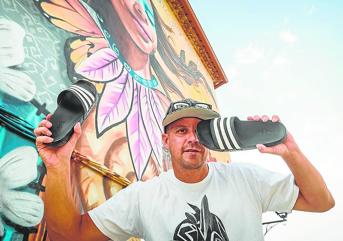 El grafitero Badi Coloreando juega con sus chanclas ante el precioso mural que ha pintado en el Ayuntamiento de Nívar.