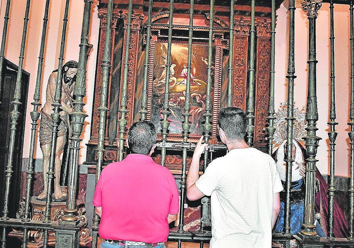 Unos curiosos analizan la obra resguardada por la artística reja de San Idelfonso.