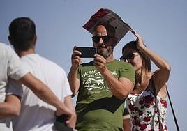 Una mujer portege del sola su compañero mientras toma una fotografía este sábado en Córdoba.