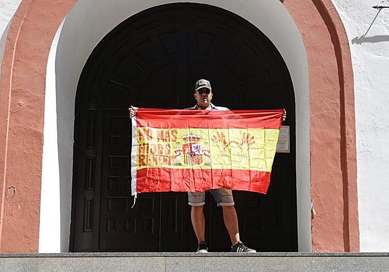 Un defensor de la custodia compartida protesta frente a la iglesia con una bandera de España que reza 'No más hijos rehenes'.