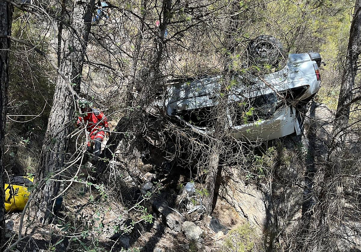 Un bombero pasa junto al coche siniestrado cerca de Moclín