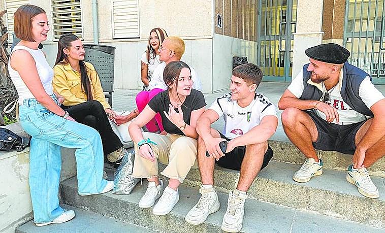 Ana y Lucía comparten risas y vivencias con sus compañeros y compañeras en la entrada de la Facultad de Trabajo Social.